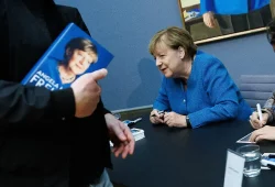 Merkel signiert Kunstpostkarten ihres Porträts im Bode-Museum